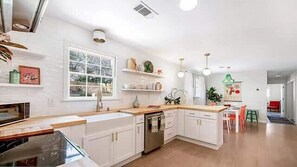 Una cucina moderna con mobili bianchi, un'ampia finestra e vista sull'esterno.