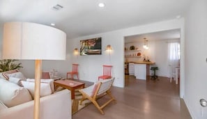 Un salon moderne avec un canapé, des fauteuils, une table et une cuisine en arrière-plan.