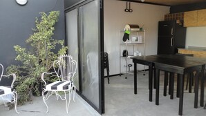 Une cuisine compacte avec un coin repas comprenant une table et des chaises, un four à micro-ondes et un réfrigérateur noir.