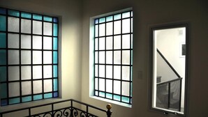 Trois fenêtres aux motifs différents, dont une avec un motif quadrillé et une autre avec un motif en réseau.
