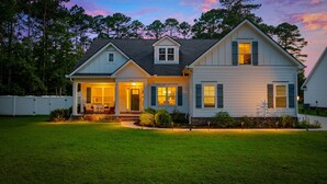A two-story house with a front porch, a garage, and a well-maintained lawn.