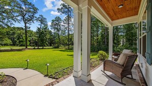 A covered patio with a view of a well-maintained lawn and trees.
