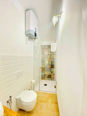 Une salle de bain équipée de toilettes, d’une cabine de douche et d’un radiateur fixé au mur.