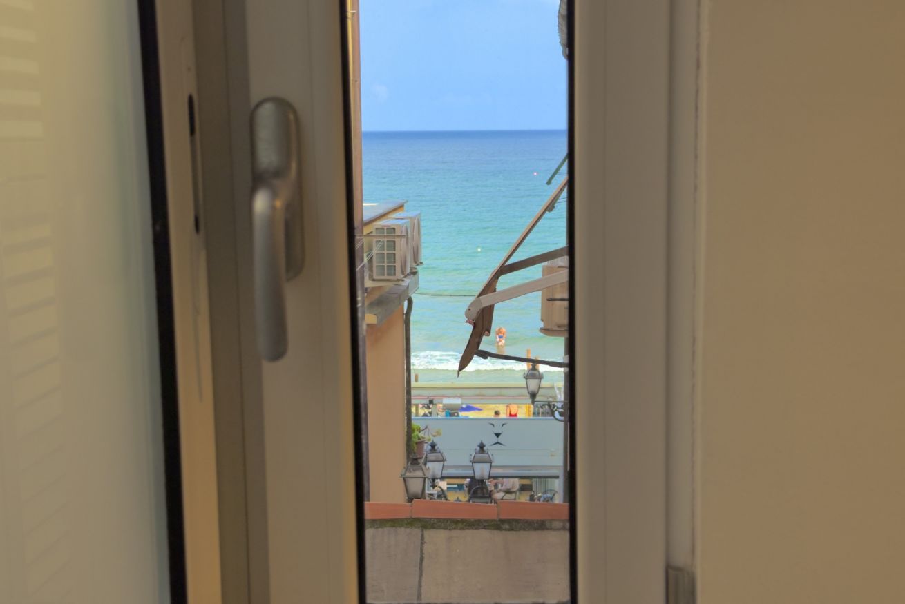 A view through a door of a balcony overlooking a beach with a clear sky.
