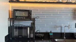 A compact kitchen with a microwave, coffee maker, and a small refrigerator. - ID URBAN LIFE LUXURY STUDIO FOREST (Setor Oeste Goiânia)