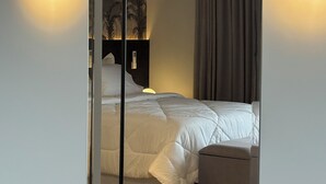 A modern hotel room with a bed, bedside table, and a mirror reflecting the room. - ID URBAN LIFE LUXURY STUDIO FOREST (Setor Oeste Goiânia)