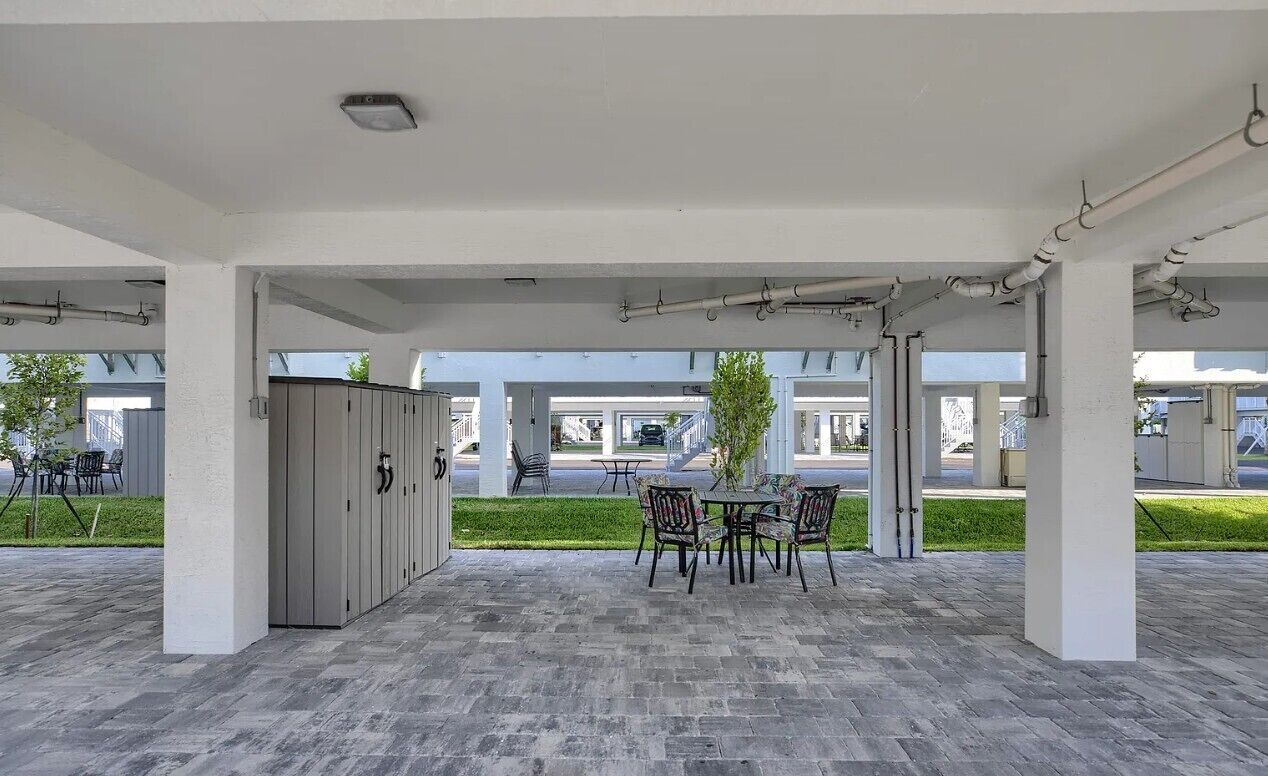 An outdoor covered patio area with a table and chairs, a grey cabinet, and a view of the street.