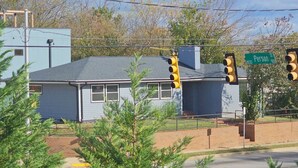 A building with a grey roof and a brick base, surrounded by greenery. - Downtown Oak City Oasis (Raleigh)