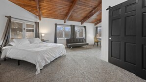 Ein Schlafzimmer mit einem Bett, einer Bank, einem Schreibtisch und einer großen, dunklen Tür.