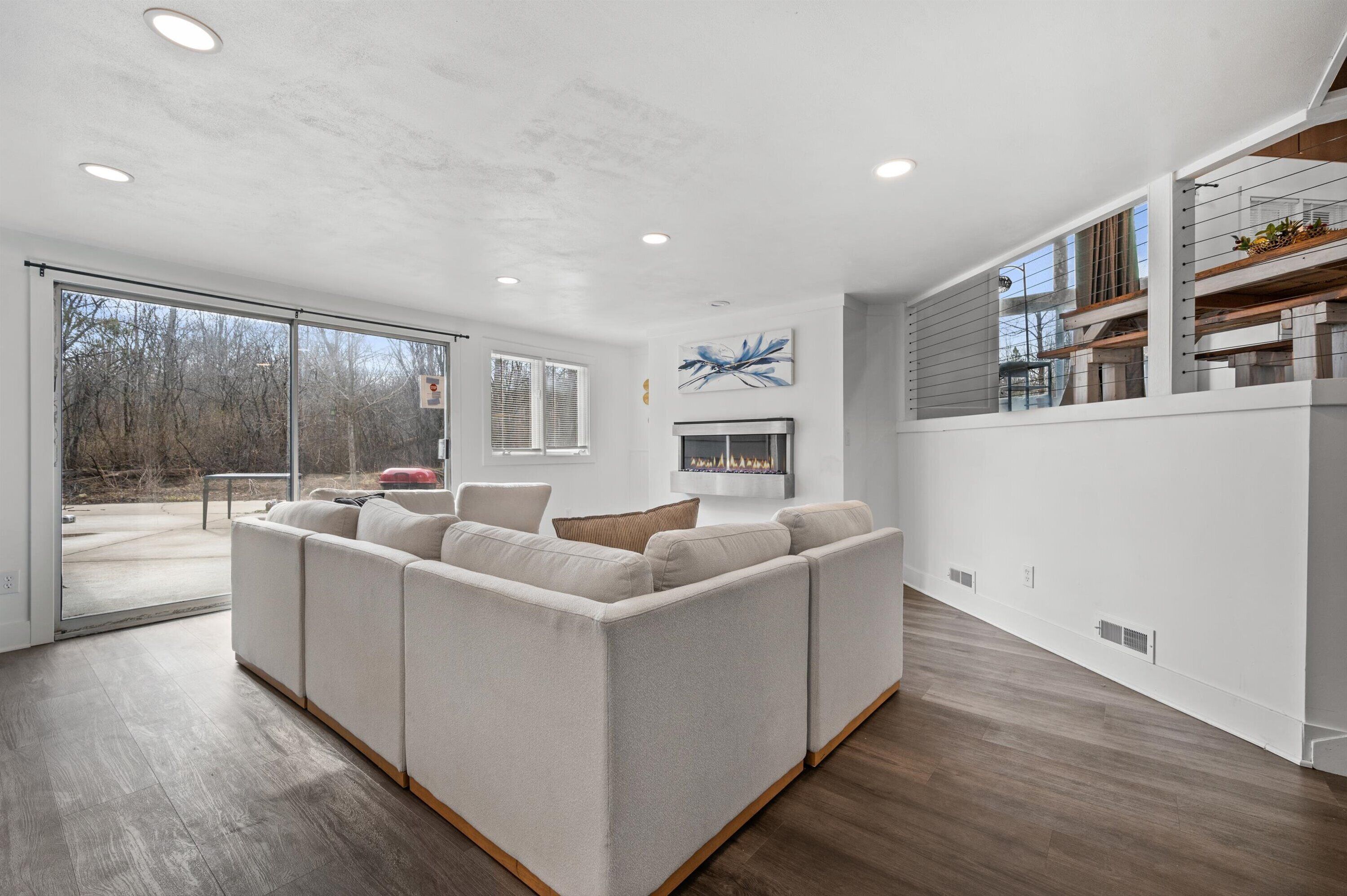 A modern living room with a sectional sofa, a fireplace, and a large sliding glass door leading to an outdoor area.