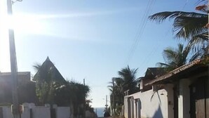 A cobblestone street lined with buildings, some with balconies and palm trees. - Pousada Casa Castelo Bed e Breakfast (Aracati)