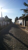 Una calle adoquinada bordeada de edificios, algunos con balcones y palmeras.