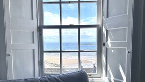A room with a view of the beach through a large window.