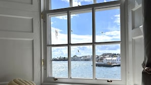 A window seat with a view of the sea and buildings.