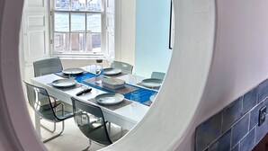 A dining area with a round window, a table set with plates, glasses, and a blue placemat.