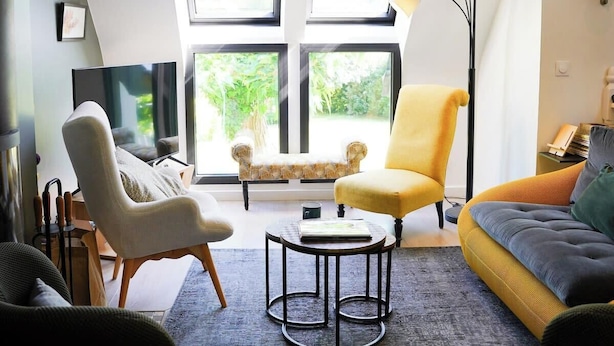 A modern living room with a large window, a sofa, a chair, and a coffee table.