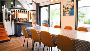 A dining area with a long table, orange chairs, and a staircase leading to an upper level.