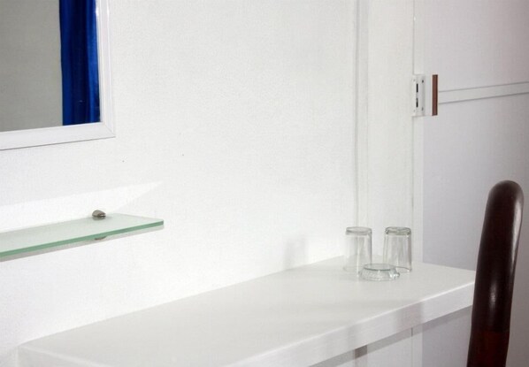 A bathroom with a white countertop, a glass shelf, and a mirror. - Hotel Torre Tuxpan (Tuxpan)