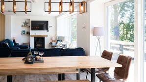 A modern living room with a large wooden table, dark blue sofa, and a fireplace.