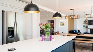 A modern kitchen with a central island, pendant lights, and a dining area with a wooden table and chairs.