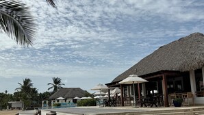 A resort with thatched-roof buildings, outdoor seating, and a pool area. - Gorgeous,  Resort Style Apartment Across Hard Rock Hotel & Casino, Punta Cana (Punta Cana)