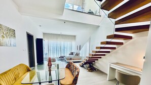 A modern living room with a glass coffee table, a sofa, and a staircase with wooden steps. - Gorgeous,  Resort Style Apartment Across Hard Rock Hotel & Casino, Punta Cana (Punta Cana)