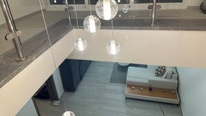 A modern interior with a glass ceiling, a white sofa, and hanging spherical lights. - Gorgeous,  Resort Style Apartment Across Hard Rock Hotel & Casino, Punta Cana (Punta Cana)