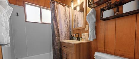 A wooden bathroom with a bathtub, toilet, and sink.