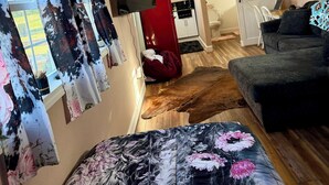 Een kamer met een plafondventilator, een bed met bloemenprint beddengoed, een rode kast en een aan de muur bevestigde televisie.
