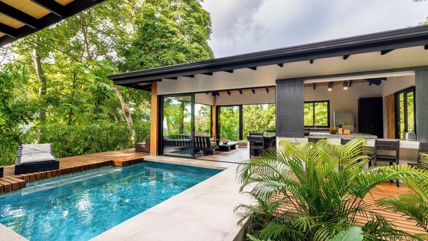 A modern outdoor pool area with a wooden deck, lounge chairs, and a covered seating area with a view of the surrounding greenery. - SANTA TERESA SURFING VILLA N°2 PRIVATE SWIMMING POOL OCEAN VIEW (Puntarenas Province)