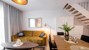 A modern living room with a sofa, a dining table, and a staircase. - Comfortable Holiday Home, Sauna, Whirlpool (Mielno)