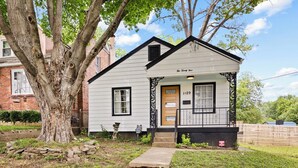A small white house with a black trim, a wooden door, and a mailbox.