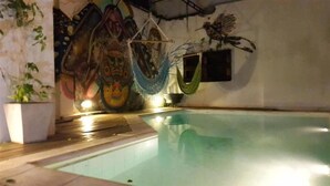 Una piscina interior con un mural en la pared y una hamaca.