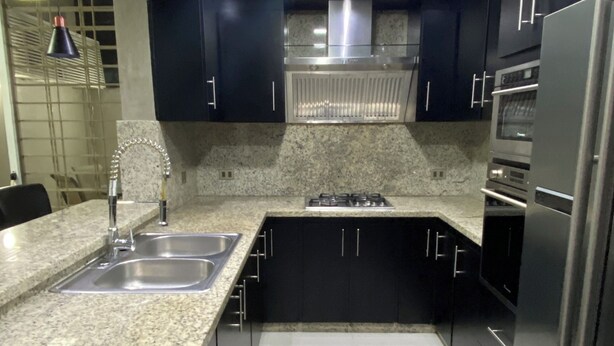 A modern kitchen with dark cabinets, stainless steel appliances, and a granite countertop.