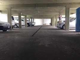 Un aparcamiento de varios niveles con pilares de hormigón y un desagüe central.