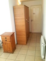 Una habitación con un armario de madera, un pequeño mueble de madera y un radiador.