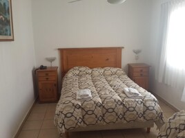 Un dormitorio con una cama, dos mesitas de noche, un cabecero de madera y un cuadro en la pared.