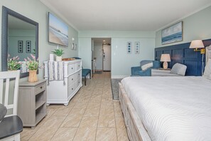 A bedroom with a bed, dresser, and a large mirror. There is a door leading to another room. - Relaxing 10th floor King Suite - Ocean Reef (Myrtle Beach)
