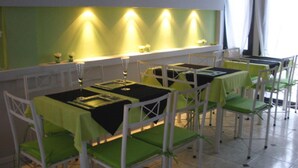A restaurant with tables set for dining, chairs, and a green wall with lighting. - Noria Hotel (Villa Carlos Paz)