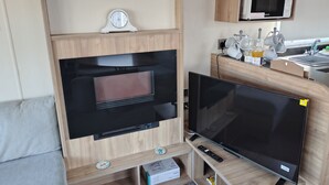 A compact living space with a built-in oven, microwave, and TV.