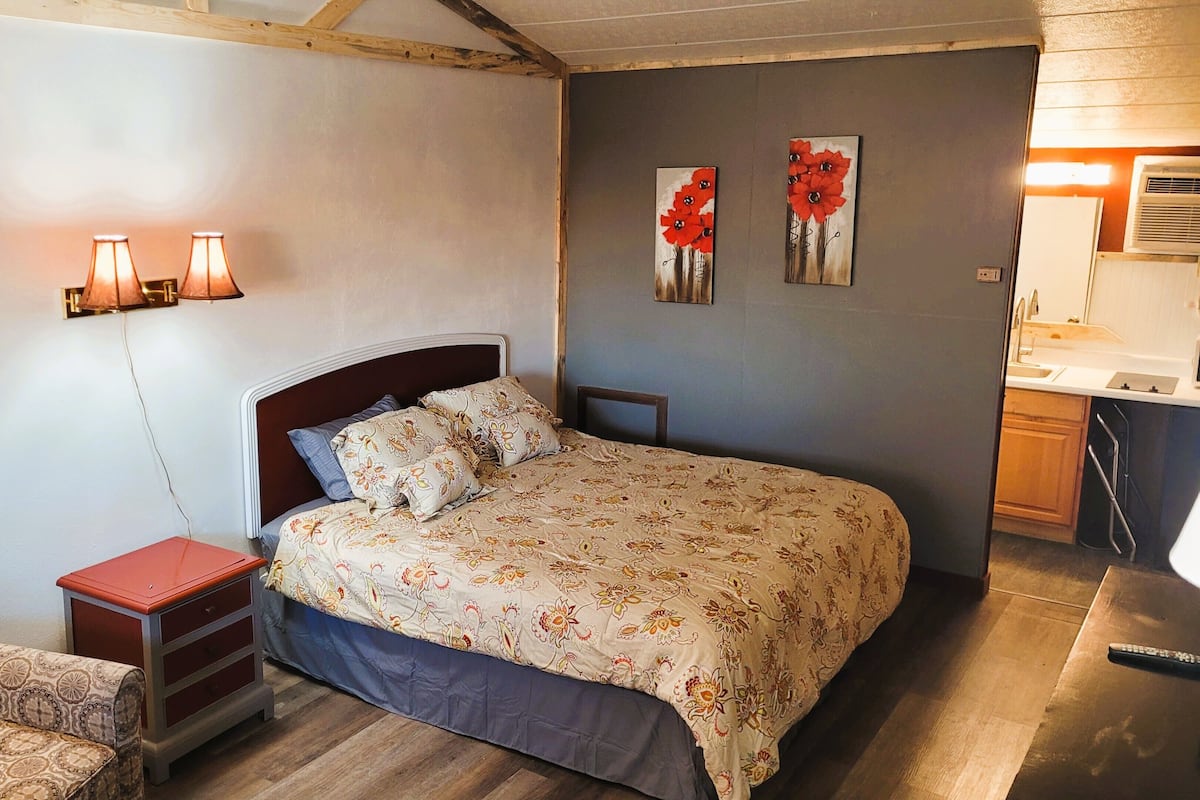A bedroom with a bed, bedside table, lamp, and a chair.