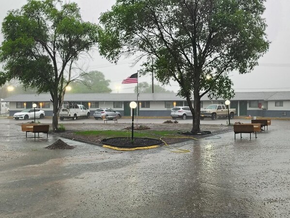 A parking lot with several cars, a flag, and a building in the background. - 1st Interstate INN (Sterling)