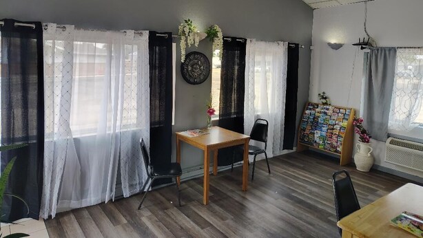 Una habitación con techo curvo, una mesa de madera, dos sillas, un tablón de anuncios y una planta en maceta.