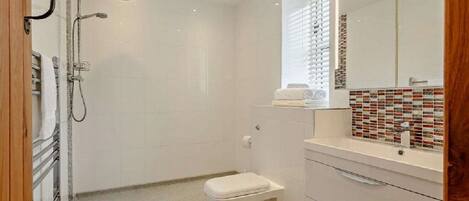 A bathroom with a shower, toilet, and vanity with a mirror.