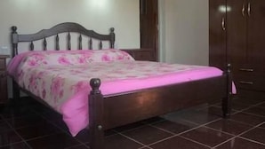 Une chambre à coucher avec un lit en bois, une armoire et deux lampes fixées au mur.