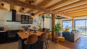 A modern kitchen with a wooden island, bar stools, and a dining table set for four. - ALESINA - MONTRICHER ALBANNE (MONTRICHER ALBANNE)