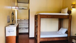 A bunk bed with a wooden frame and white bedding, a desk with a white cloth and a pen holder, and a wall-mounted air conditioning unit. - Habitación 2 (Sierpe)