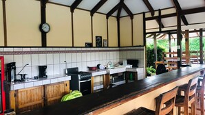 A kitchen with a long counter, wooden cabinets, a clock, and a sign that says "ALL you need is coffee." - Habitación 2 (Sierpe)