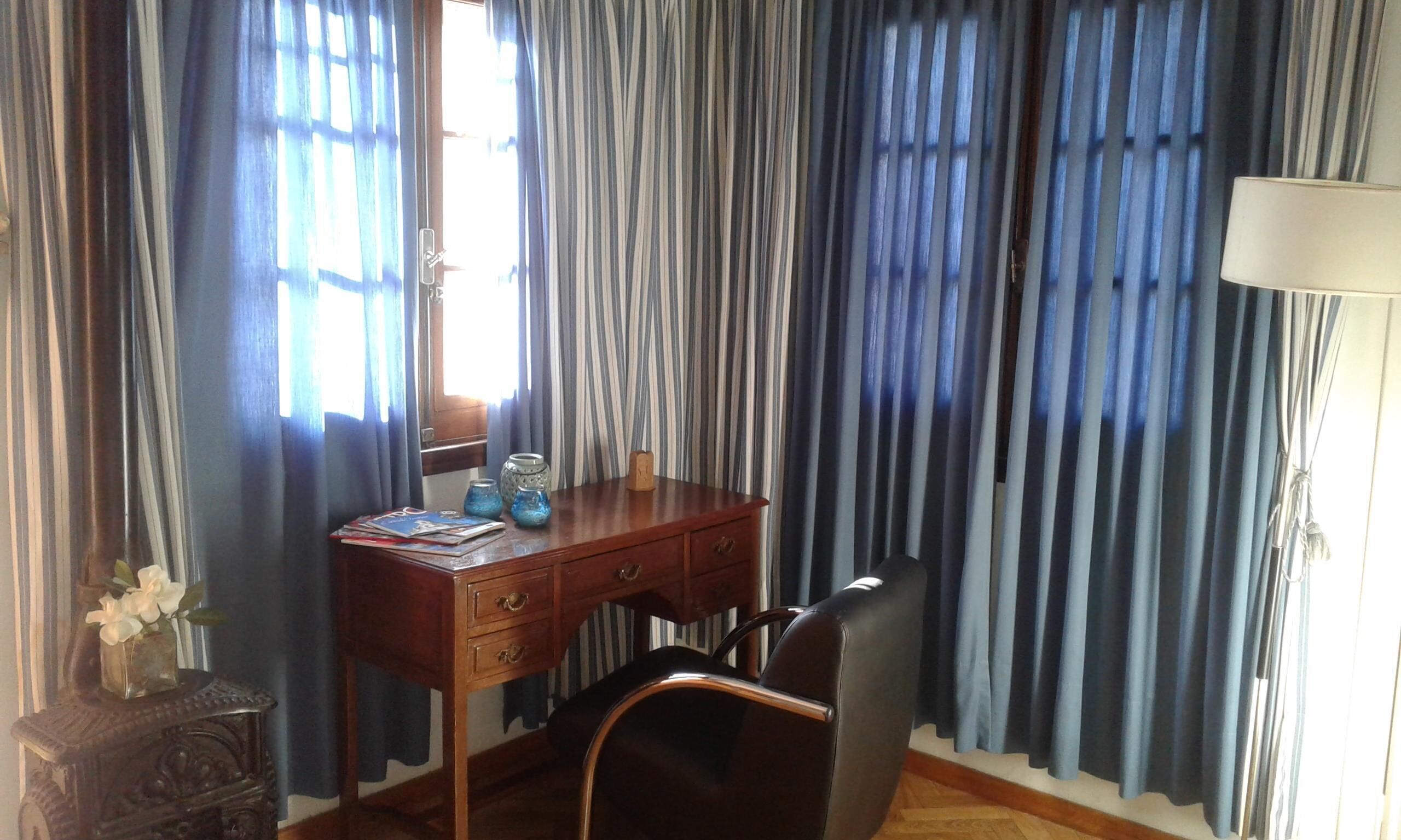 A room with a wooden desk, a chair, and a lamp.