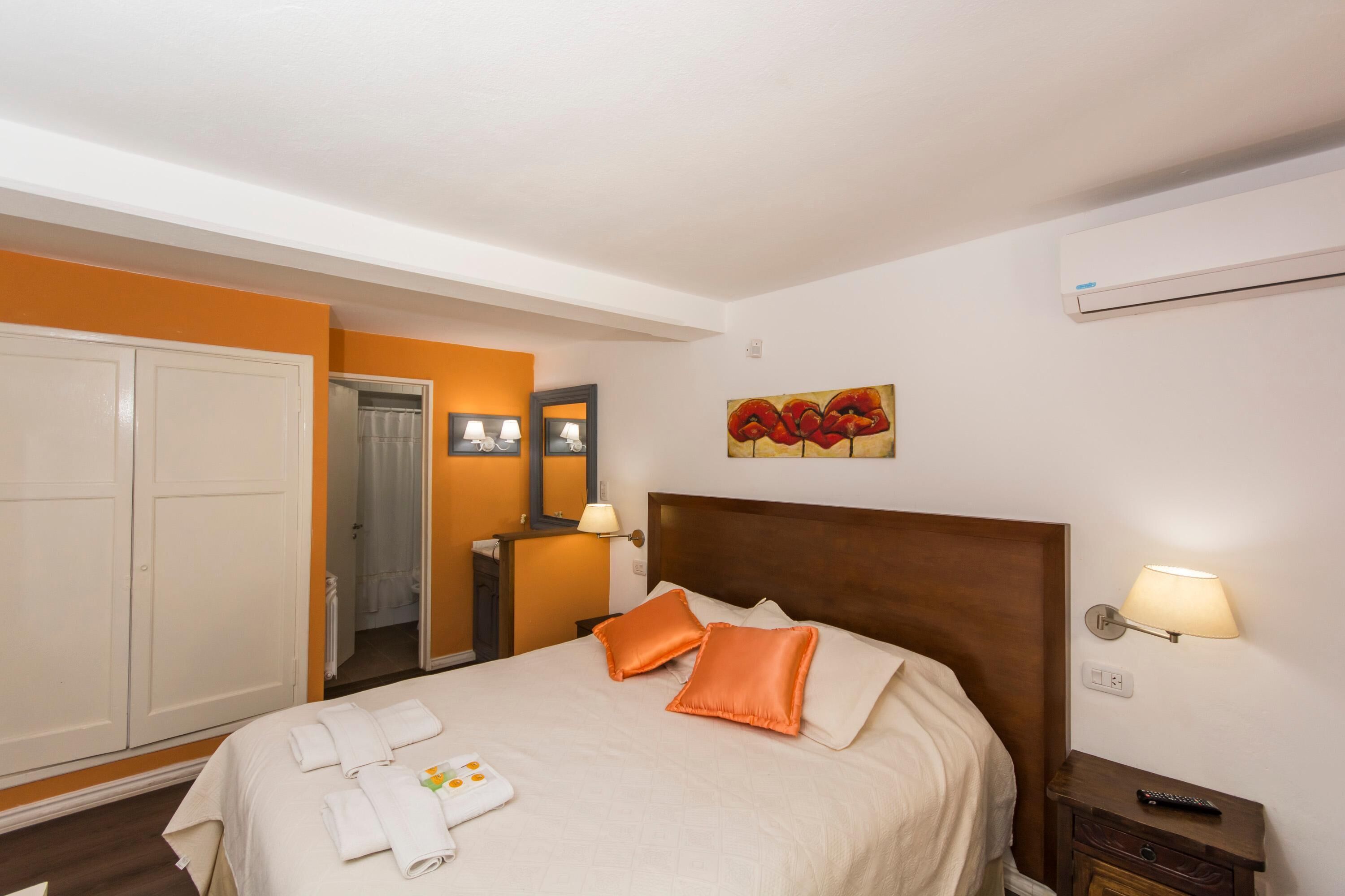 Una habitación de hotel con cama, mesita de noche, lámpara, un cuadro y un armario.